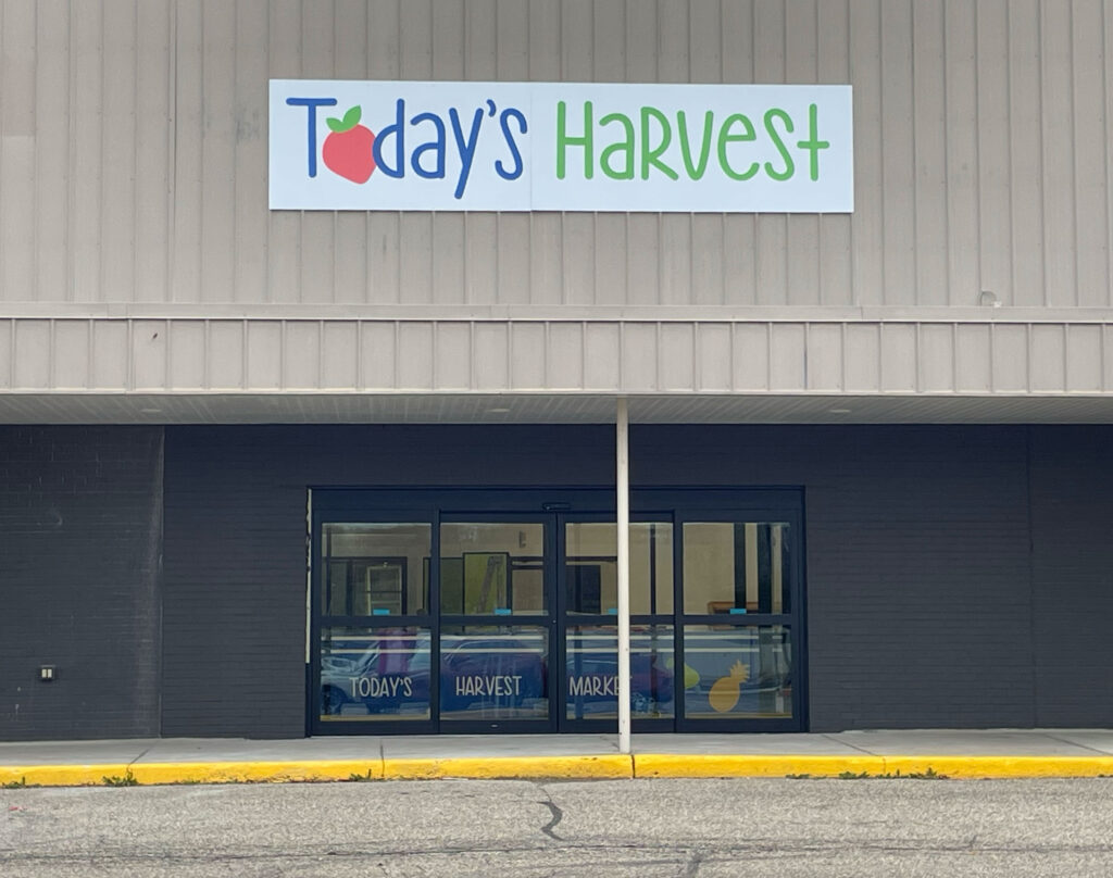 Photo of the exterior of a building with glass doors and a sign above that says Today's Harvest